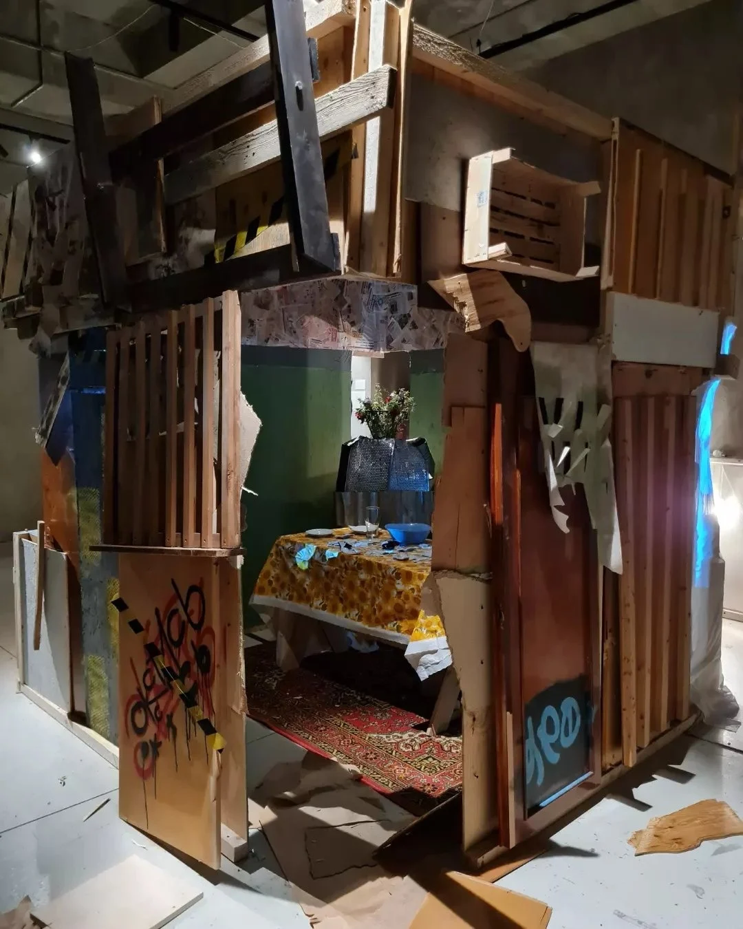 The hut’s interior: table with broken plates, graffiti on the door