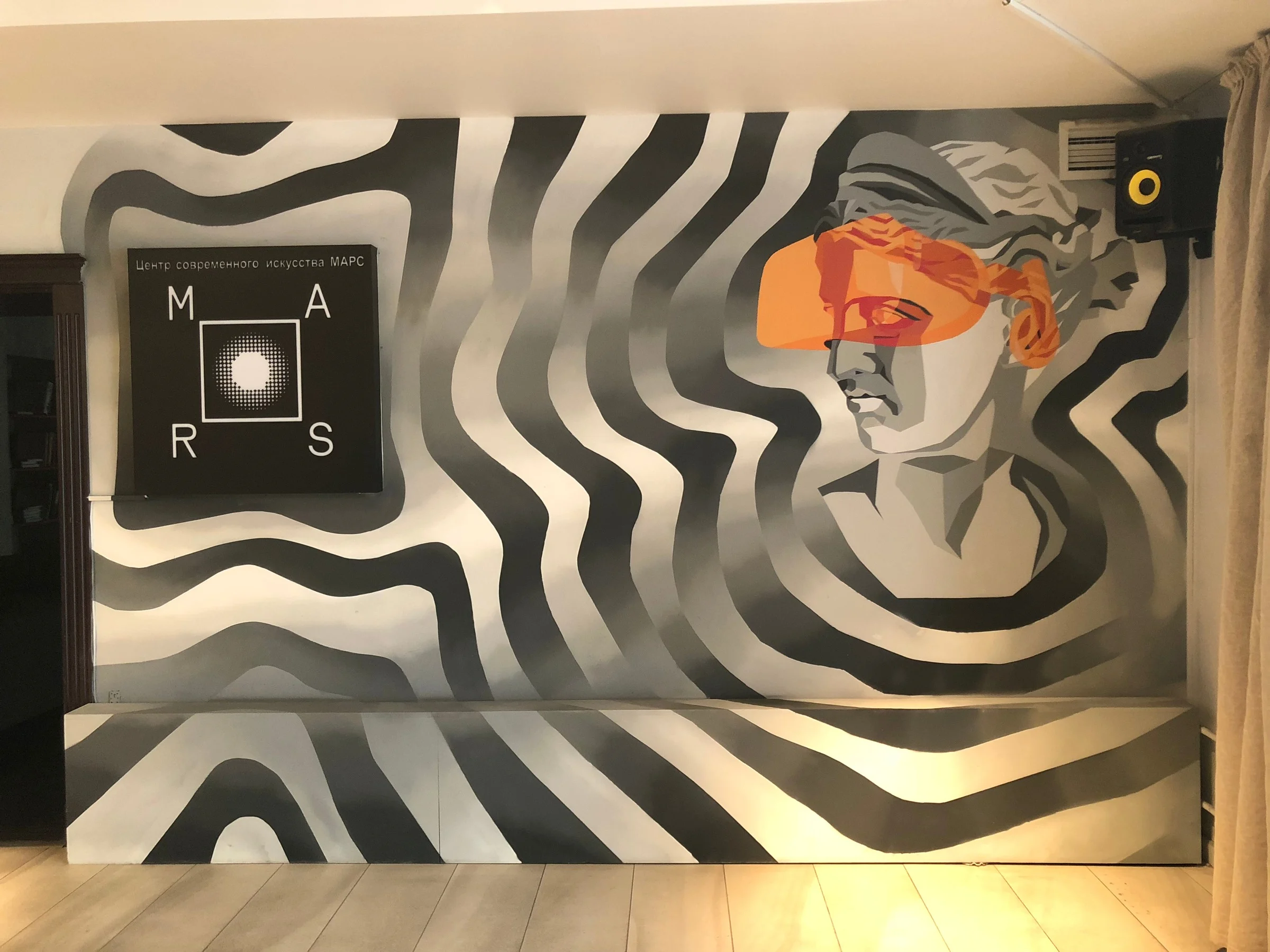 Techno-Antiquity mural at MARS: a classical bust with an orange visor amid black-and-white waves